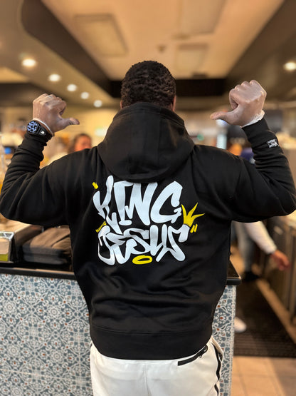 African American man in full color, showing the back of the King Jesus Hoodie with hands up and thumbs pointing at the design—bold Christian streetwear with a faith-inspired message.