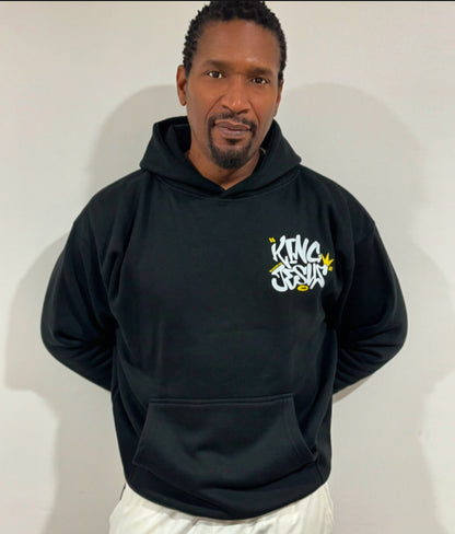 African American man posing with the King Jesus Hoodie, hands behind his back, showcasing bold Christian streetwear and faith-inspired fashion.