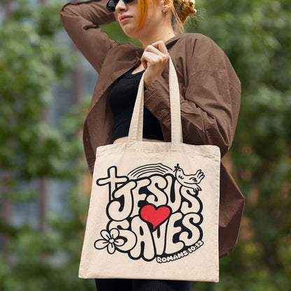 Woman holding a tote bag with 'Jesus Saves' design outdoors